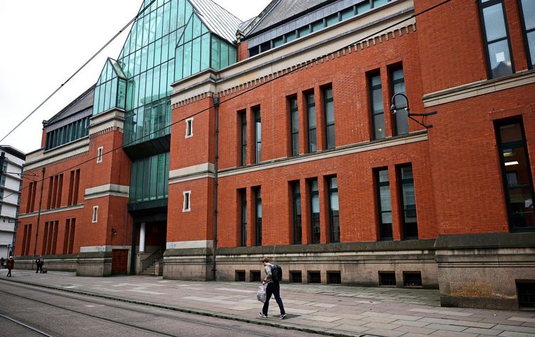 Außenansicht des Crown Courts an der Minshull Street in Manchester, Großbritannien. Das Gebäude aus rotem Backstein mit großen Fenstern und einer Glasfassade im oberen Bereich. Personen gehen auf dem Gehweg vorbei.