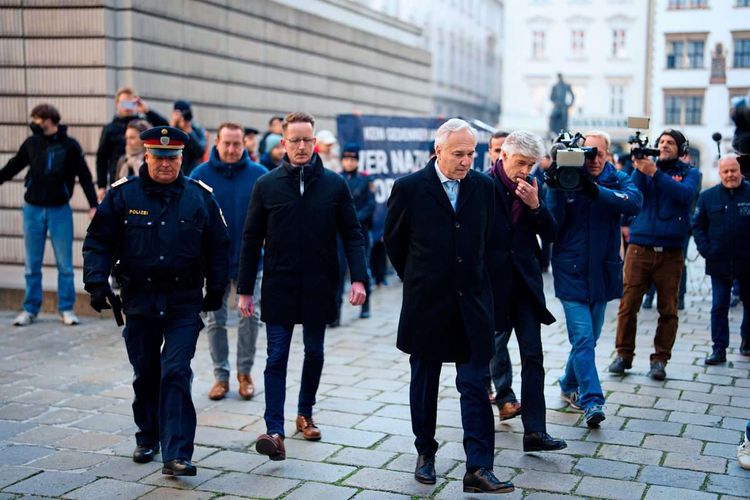 Walter Rosenkranz geht vom Shoah-Denkmal am Wiener Judenplatz weg, im Hintergrund eine Menschenkette.