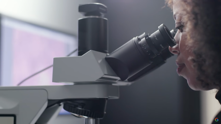 Eine Frau sieht in den Sucher eines großen Mikroskops
