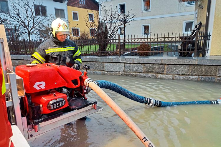 Ein Feuerwehrmann pumpt mit einer Maschine Wasser ab.