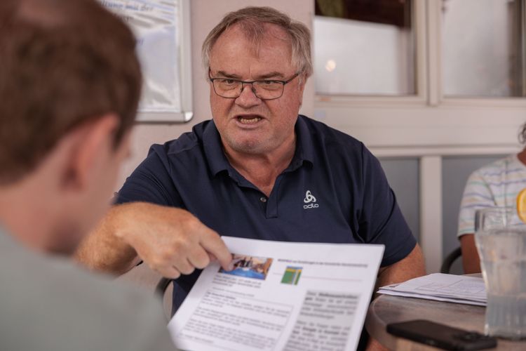 Hannes Ömer tippt mit einem Finger auf einen weißen Zettel