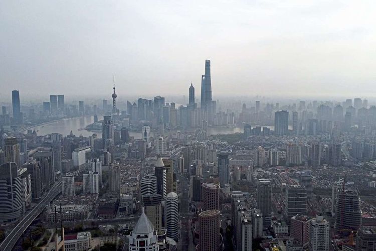 Eine Luftaufnahme von Shanghai, eine Flussschleife zieht sich durchs Bild, am Horizont stehen Wolkenkratzer.