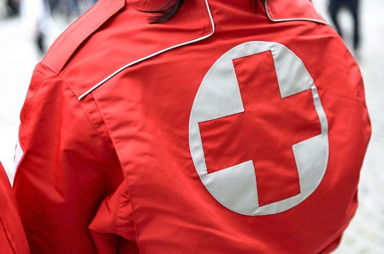 Eine Mitarbeiterin des Roten Kreuzes trägt eine rote Jacke mit rotem Kreuz auf weißem Hintergrund.