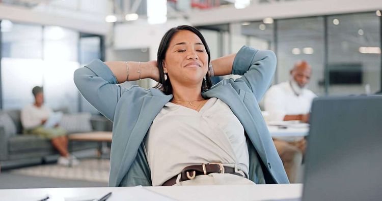 Eine junge Frau liegt mit geschlossenen Augen entspannt in einem Bürostuhl