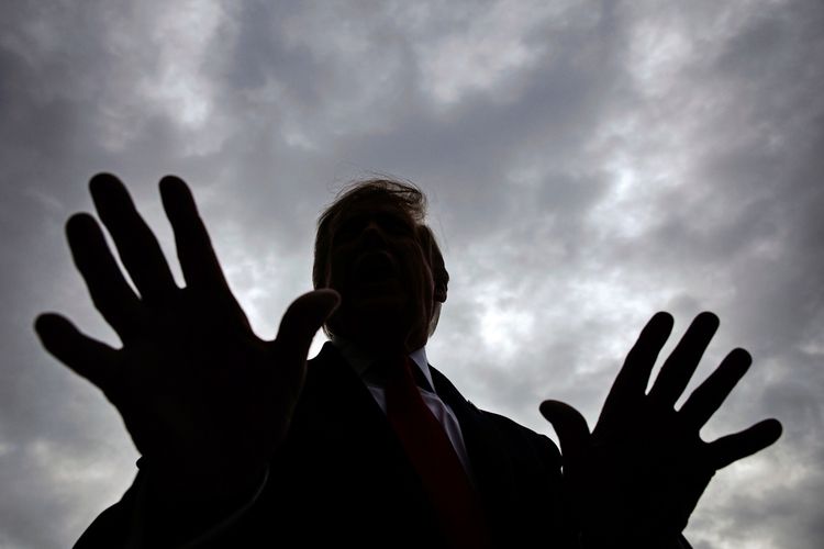 Eine Silhouette einer Person mit erhobenen Händen vor einem wolkenbedeckten Himmel.