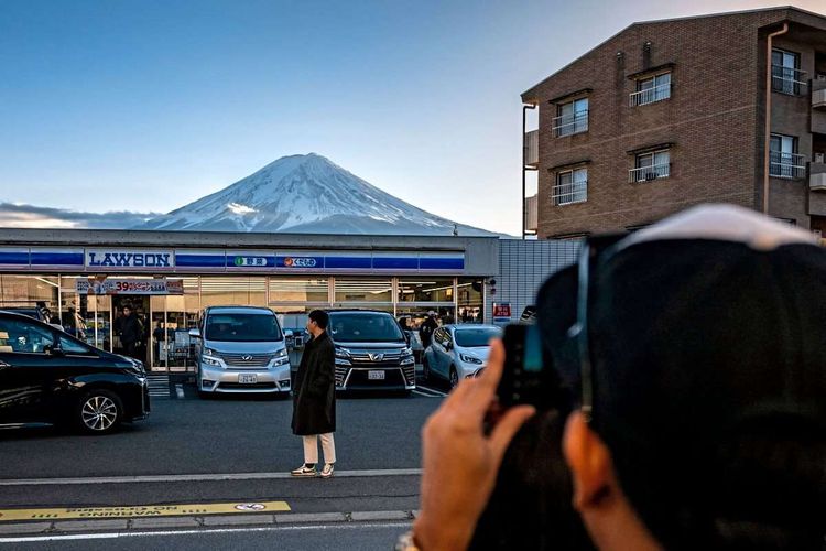 Der Aussichtspunkt, an dem nun der Sichtschutz aufgestellt wird, ist besonders beliebt, weil der majestätische Vulkan hinter einem der in Japan allgegenwärtigen Lawson-Supermärkte aufragt.