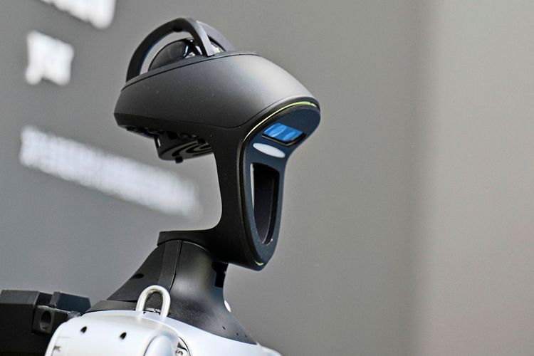 Ein moderner, schwarz-silberner Roboterkopf mit Kamerasensoren wird angezeigt. Der Hintergrund ist unscharf.