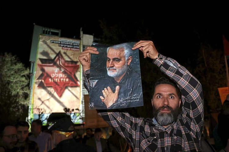 Ein Mann hält ein Foto von Ghassem Soleimani hoch