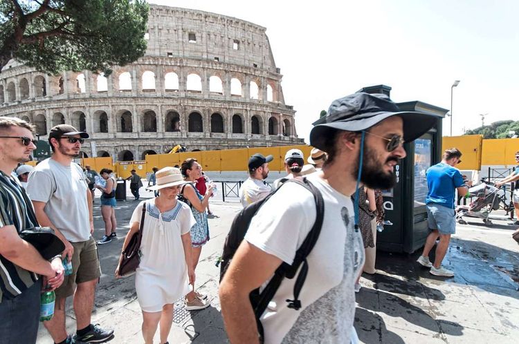 Zu sehen ist das Kolosseum mit Reisenden im Vordergrund.