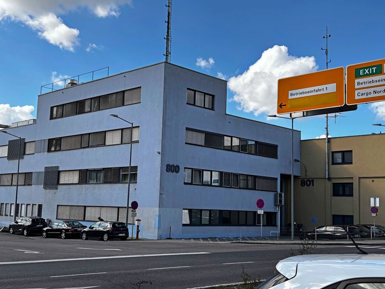 Ein modernes, mehrstöckiges Gebäude mit den Hausnummern 800 und 801. Davor stehen mehrere geparkte Autos. Im Vordergrund Straßenbeschilderung mit Hinweis auf 