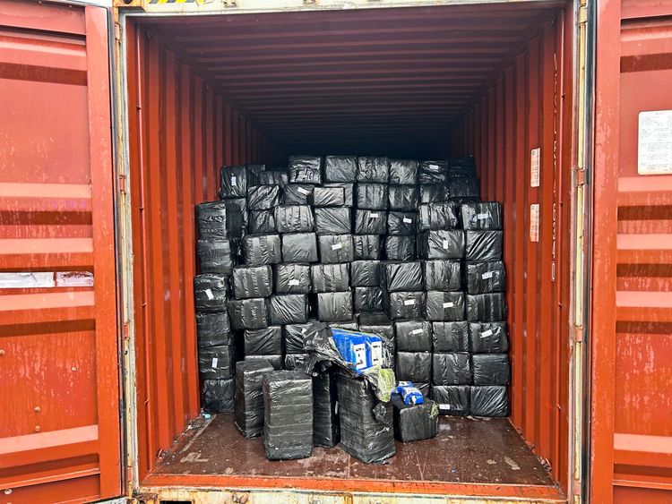 Eine rote Frachtcontainer-Ladung, gefüllt mit gestapelten schwarzen, in Plastik verpackten Paketen. Die Aufnahme stammt von der deutschen Zollverwaltung und zeigt die beschlagnahmte Fracht, die über acht Tonnen Kokain während eines Einsatzes in Wilhelmshaven, Deutschland, enthält.