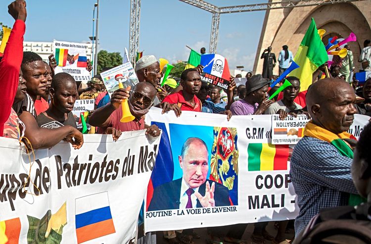 Malische Demonstranten halten ein Plakat mit dem Gesicht Putins in die Kamera.