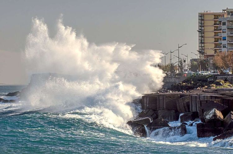 Eine kräftige Welle bricht an der Felsenküste einer Stadt