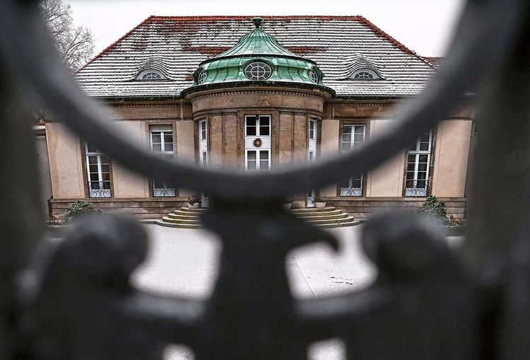 Blick durch schwarzes Tor auf Eingang mit Stiegen davor.