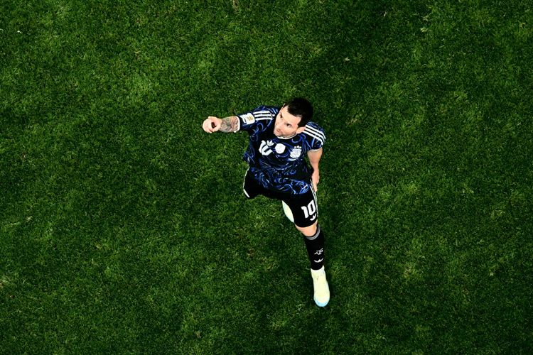 Ein Fußballspieler im Trikot der argentinischen Nationalmannschaft (Nummer 10) steht auf dem Spielfeld und blickt jubelnd in die Kamera. Der Rasen ist gleichmäßig grün.