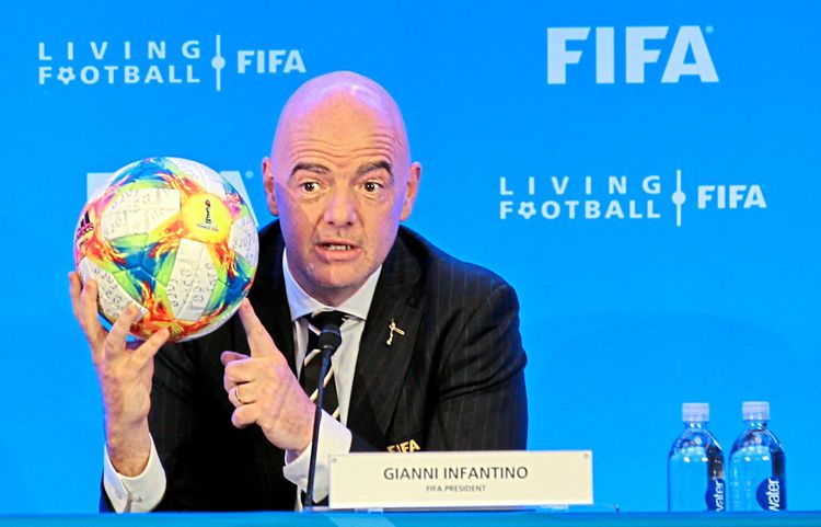 Gianni Infantino hält einen Fußball bei einer Pressekonferenz