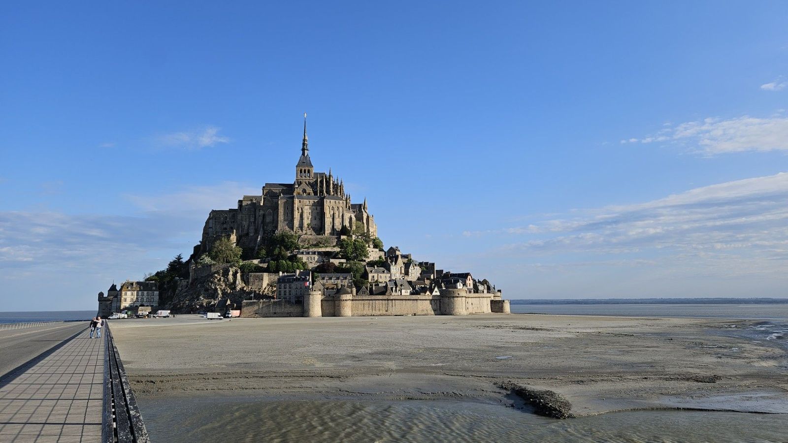 Ein historsiches Bauwerk auf einer Sandinsel, eine Brück führt dorthin, es ist Ebbe.