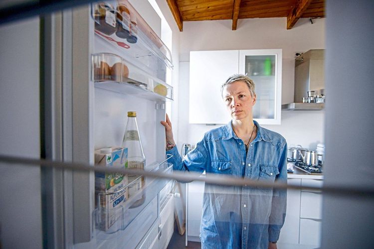 Eine Frau blickt in einen leeren Kühlschrank.