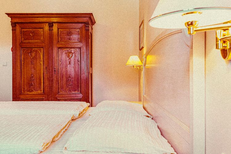 Ein Zimmer mit Doppelbett und altem Holzkasten
