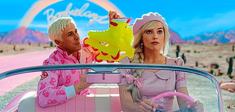 Ken (Ryan Gosling) und Barbie (Margot Robbie) fahren in einer Filmszene gemeinsam im Auto – Barbie am Steuer, Ken hält gelbe Rollerblades hoch