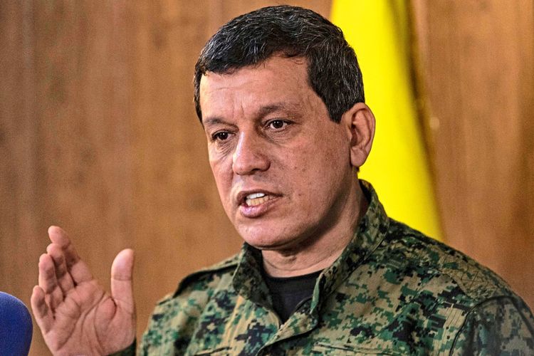 Ein Mann in Militäruniform spricht während einer Pressekonferenz. Im Hintergrund ist eine gelbe Fahne teilweise sichtbar.