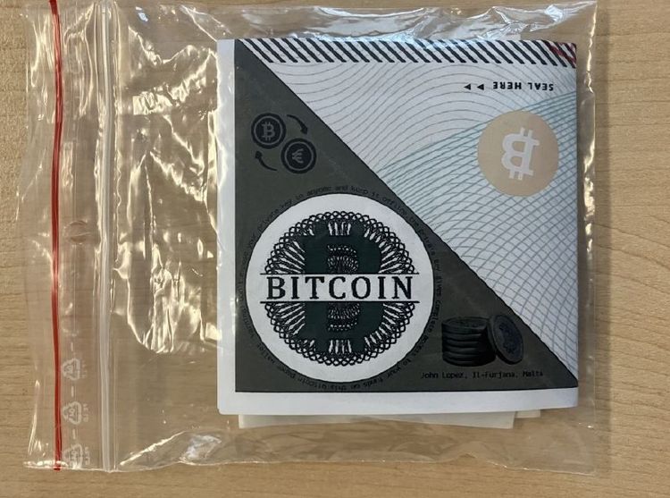 In einem Plastiksackerl liegt zusammengefaltet eine Bitcoin-Paper-Wallet.