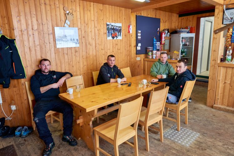 Vier Männer beim Kaffeetrinken in der Skihütte.