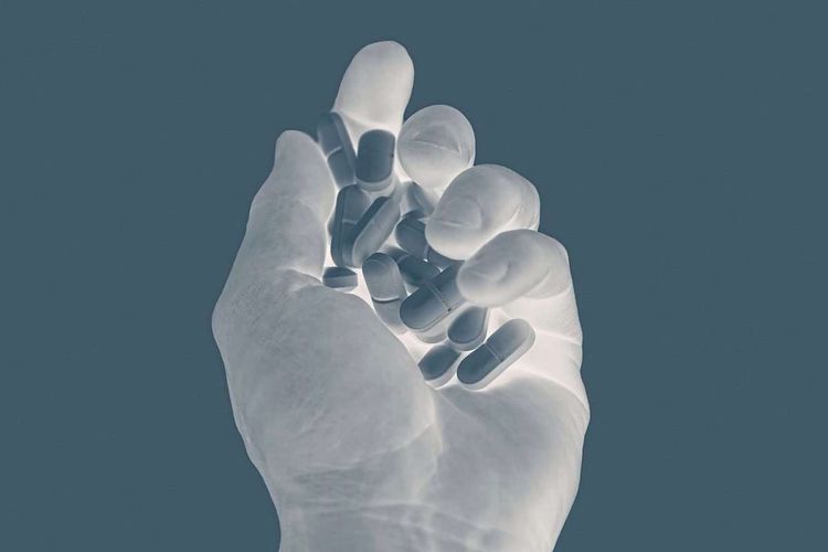 Ein Röntgenbild einer Hand in der verschiedene Tabletten lieben.