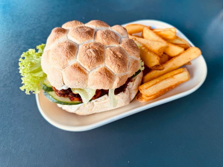Weckerl, Salatblatt, Oktopus gegrillt und klein geschnitten, Pommes auf einem Teller