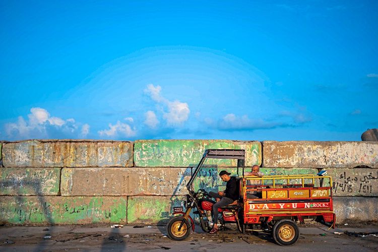 Ein dreirädriges Transportmoped steht am Hafen von Gaza-City. Zwei Männer warten.