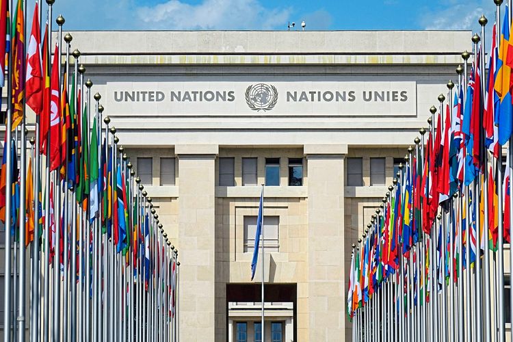 Das Gebäude der Vereinten Nationen in Genf mit Fahnen davor.
