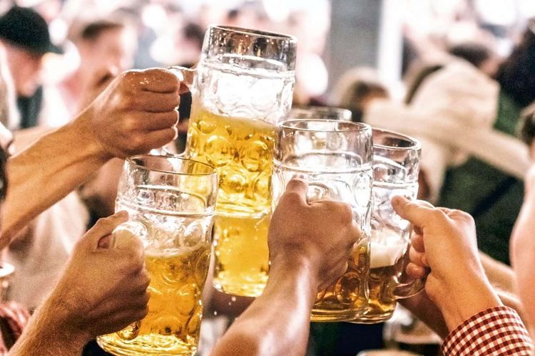 group of people clinking beer glasses in beer hall at Beer Fest in munich