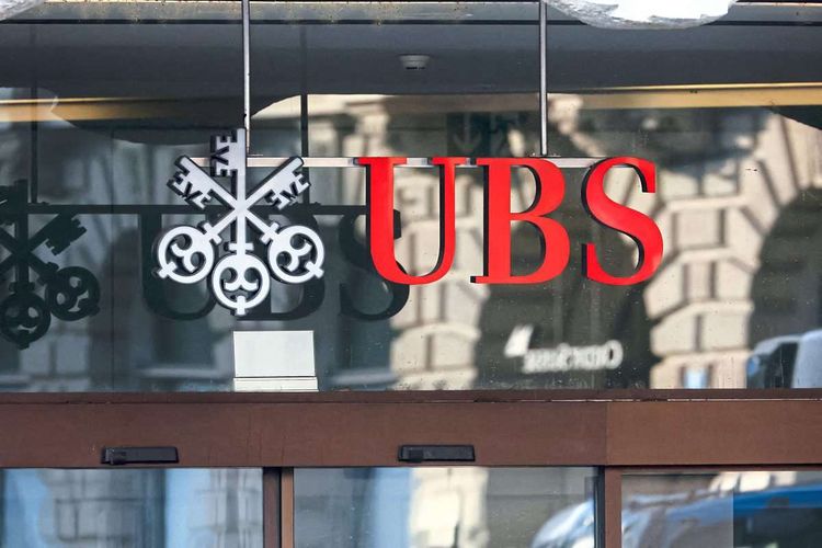 Das Logo der UBS am Eingang einer Filiale. Schräg dahinter spiegelt sich der Schriftzug 
