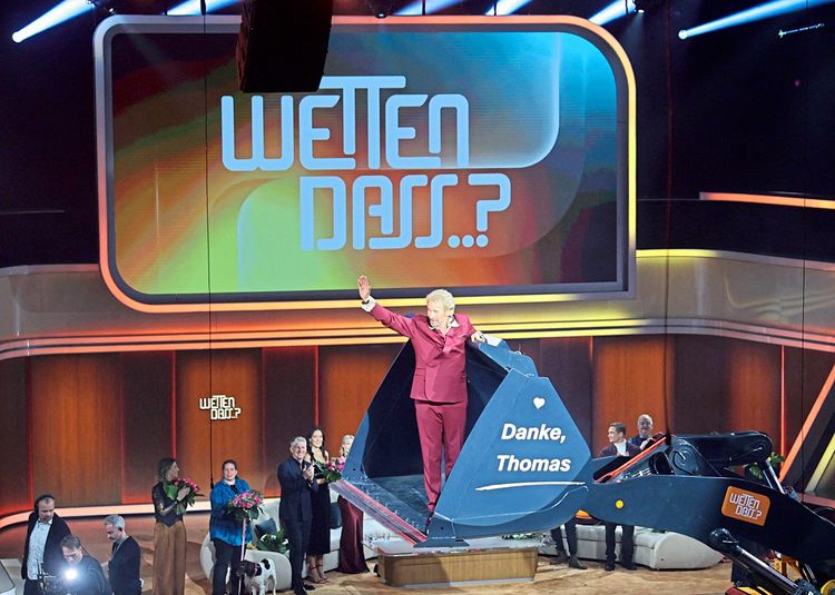 Thomas Gottschalk steht auf einer Baggerschaufel und winkt dem Publikum zu. Die Stargäste klatschen im Hintergrund.