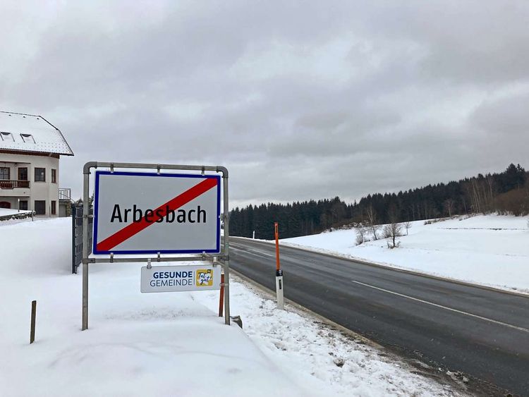 Eine Ortstafel in Schneelandschaft mit dem durchgestrichenen Gemeindenamen 