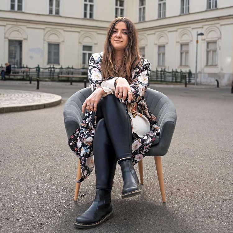 Andrea Laub sitzt auf einem Sessel auf einem Platz in Wien.