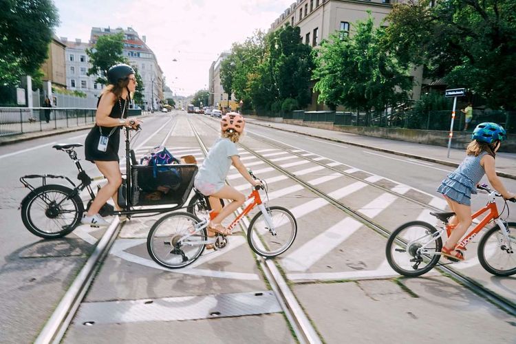 Elli und ihre zwei Töchter überqueren eine große Straße mit den Fahrrädern