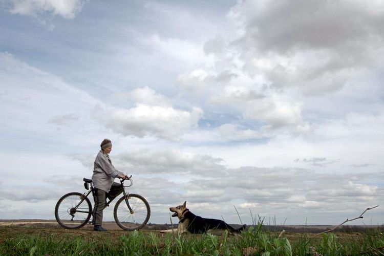Frau auf Fahrrad mit Schäferhund.