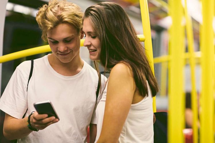 Junges Paar in der Wiener U-Bahn schaut aufs Handy