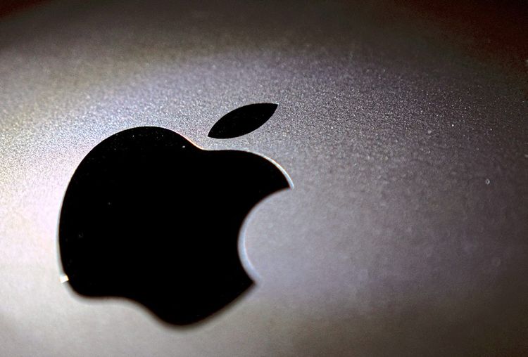 Ein schwarzes Apple-Logo ist auf einer silbernen Oberfläche zu sehen.