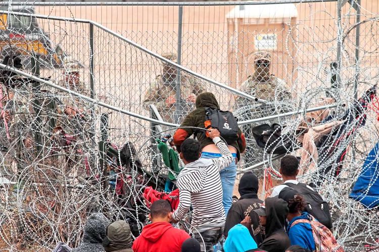 Bei Ciudad Juárez kämpfen sich Migranten durch den Grenzzaun.