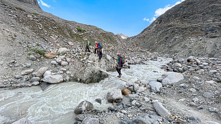 Wanderer überqueren Fluss im hochalpinen Gebirge.