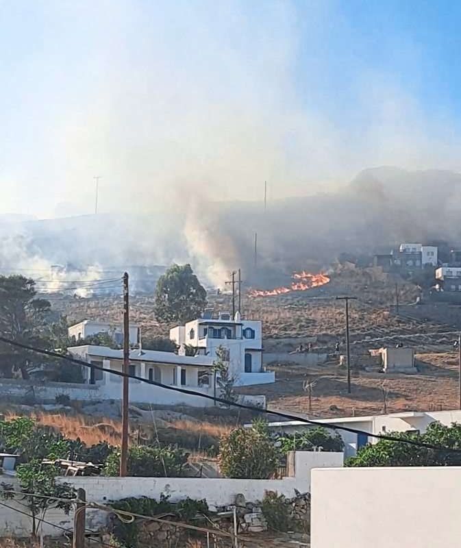 Mehrere Häuser mit Flammen und Rauch im Hintergrund.
