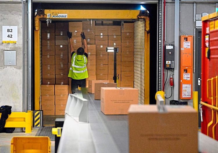 Ein Arbeiter in einem Logistikzentrum stapelt Pakete in einem Lastwagen. 