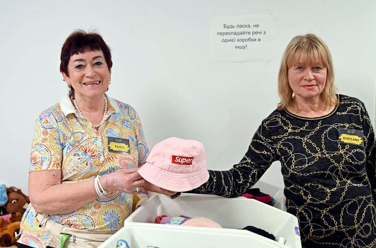 Zwei Ukrainerinnen halten in der Kleiderausgabe des Communitycenters von Train of Hope in Wien eine  Hut mit der Aufschrift 