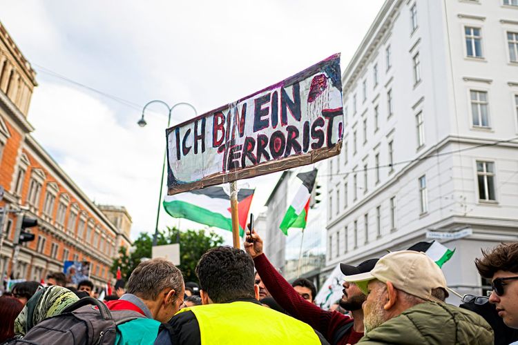 Ein Mann bei einer propalästinensischen Demonstration in Wien hält ein Schild mit der Aufschrift 