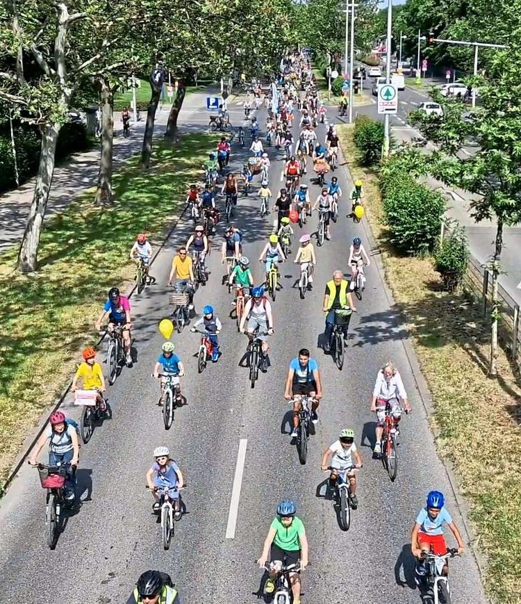 Viele Kinder und Erwachsene auf eine zweispurigen Straße in Wien beim Radfahren.