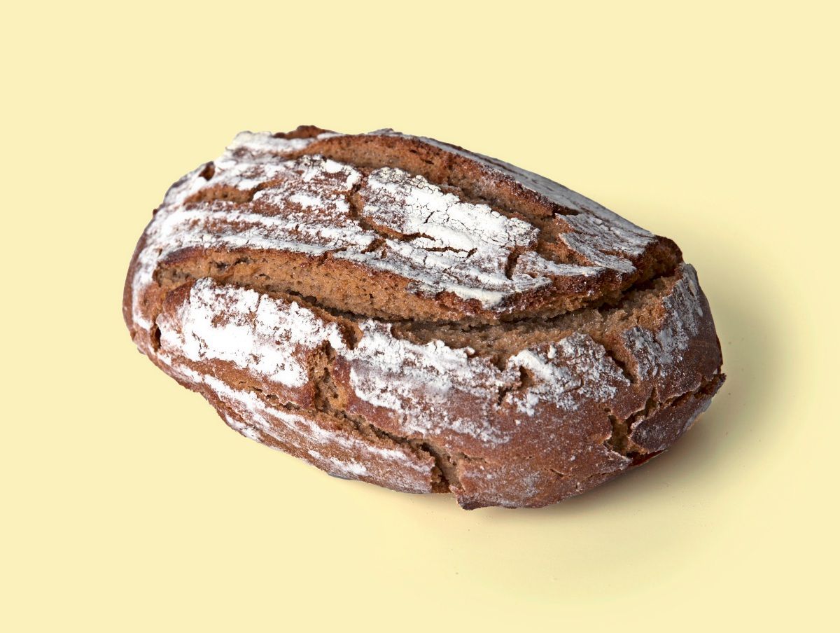 Ein Laib Roggenbrot mit bemehlter Kruste vor hellem Hintergrund.