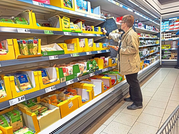 Frau greift in Kühlregal in Supermarkt