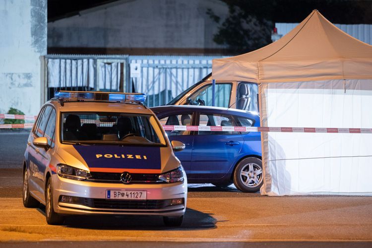 Ein Polizeiauto vor einem Auto unter einem weißen Zelt.